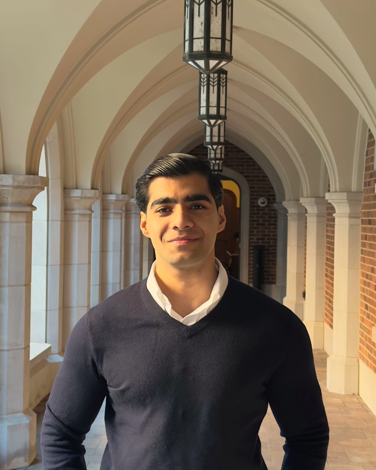 man in a sweater in front of a colonade 